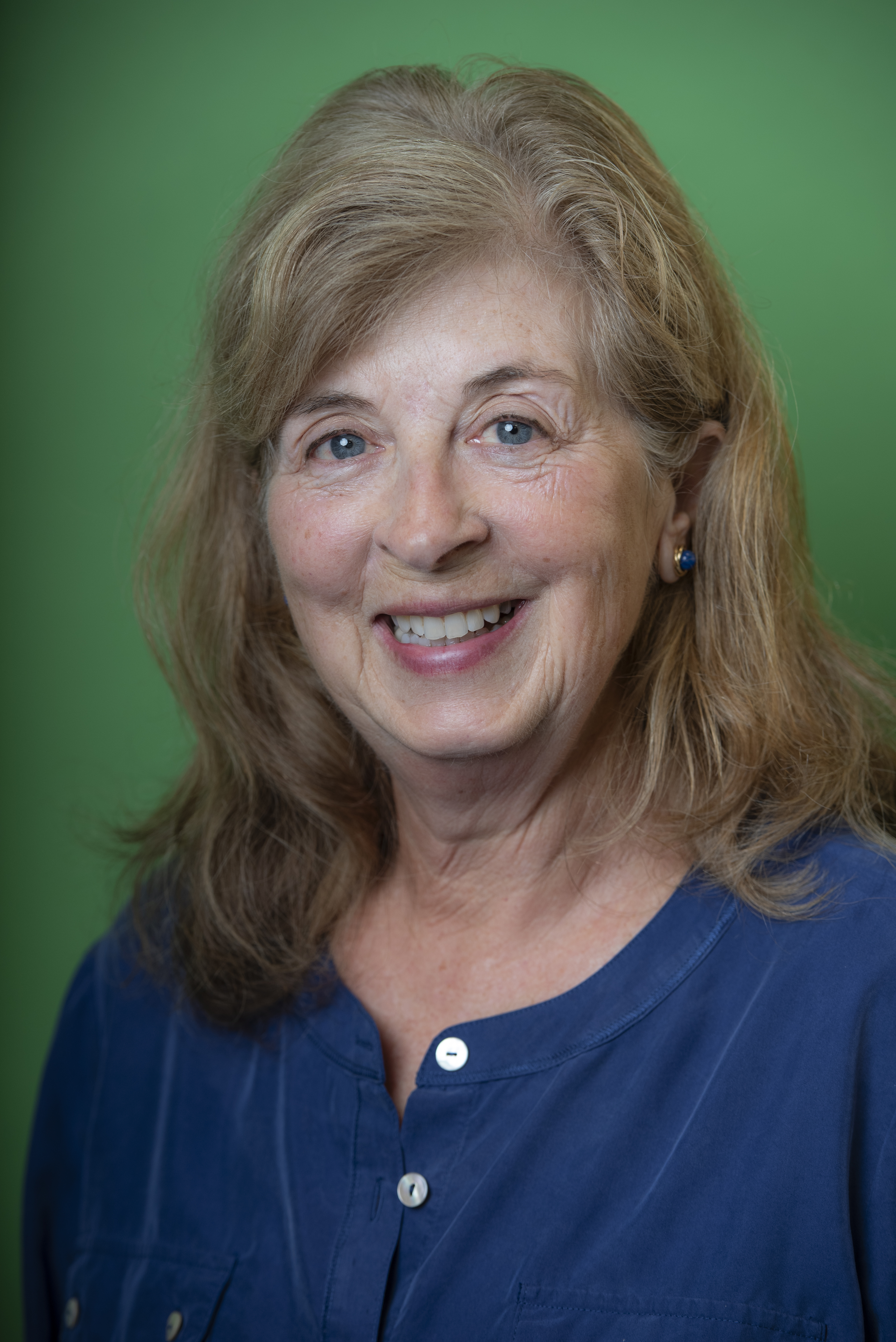 Headshot of Mary Ordal wearing a blue blouse in front of a green background