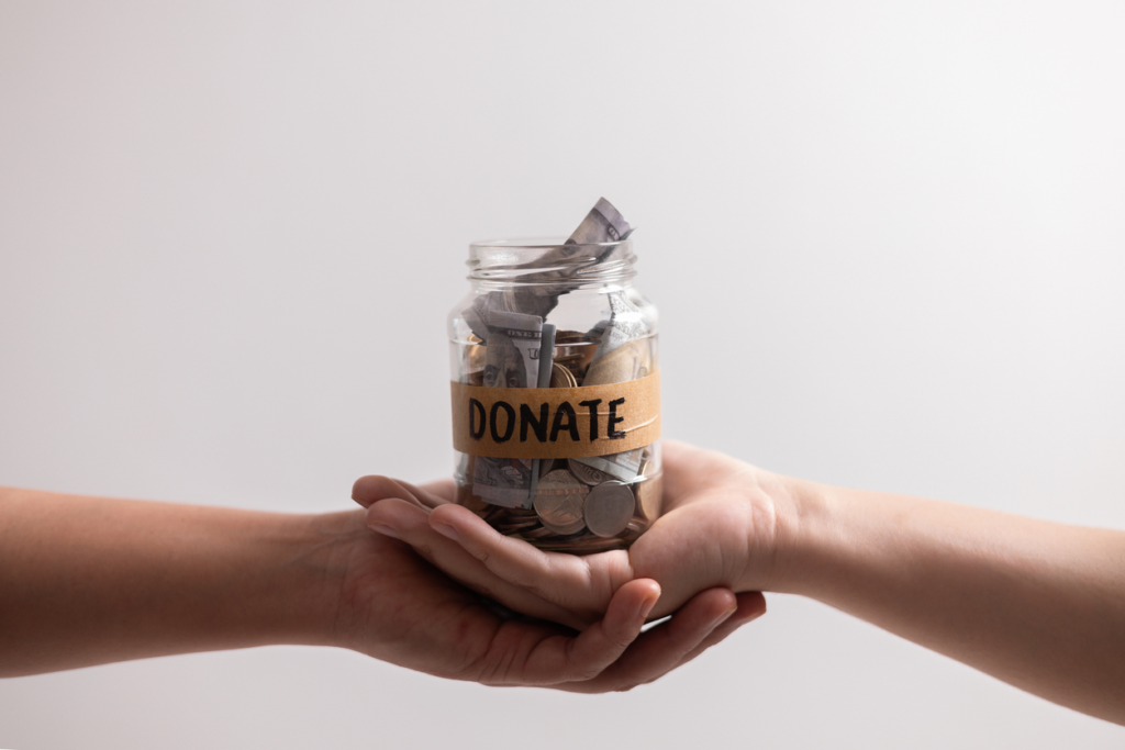 Hands holding a jar filled with money with a label that says "donate"